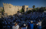Jewish men hold Israeli flags as they dance at Damascus Gate in Jerusalem's Old City, during Jerusalem Day celebrations, June 5, 2024. (Chaim Goldberg/Flash90)