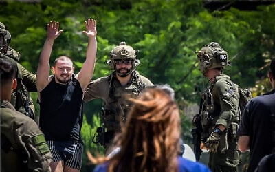 Rescued hostage Almog Meir Jan raises his hands in celebration as he is escorted from an IDF helicopter on arrival at Sheba Medical Center in Ramat Gan, June 8, 2024. (Avshalom Sassoni/Flash90)
