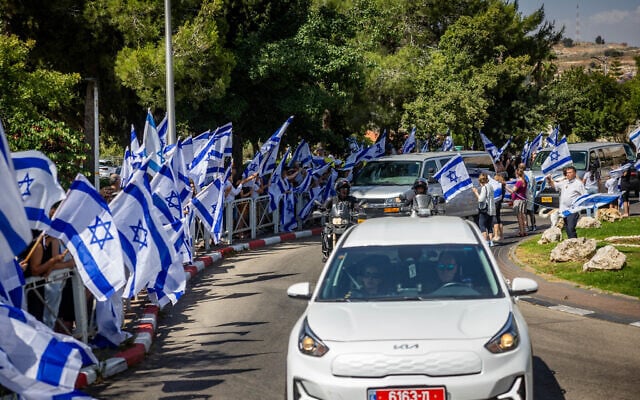 People wave the Israeli flag as they pay their respect to counter-terror officer Arnon Zamora, who was killed in battle on June 8 during a special operation to rescue four Israeli hostages from Gaza, outside his family home in Mevasseret Zion, June 9, 2024. (Yonatan Sindel/Flash90) People wave the Israeli flag as they pay their respect to counter-terror officer Arnon Zamora, who was killed in battle on June 8 during a special operation to rescue four Israeli hostages from Gaza, outside his family home in Mevasseret Zion, June 9, 2024. (Yonatan Sindel/Flash90)
