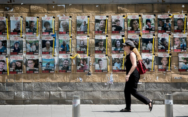 A person walks past photographs of people held hostage by Hamas terrorists in Gaza, outside the Ministry of Defense in Tel Aviv. June 16, 2024 (Miriam Alster/FLASH90) A person walks past photographs of people held hostage by Hamas terrorists in Gaza, outside the Ministry of Defense in Tel Aviv. June 16, 2024 (Miriam Alster/FLASH90)