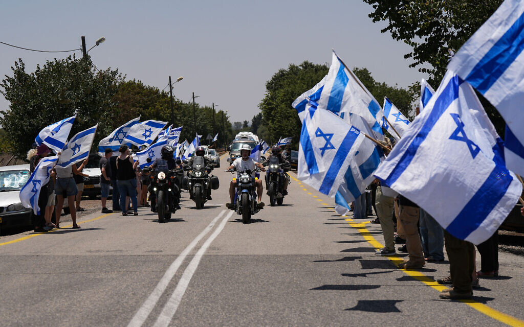 People holding Israeli flags as they pay their respect to IDF soldier Sgt. Eyal Shynes who was killed in the Gaza Strip, outside Kibbutz Afik, June 28, 2024. (Ayal Margolin/Flash90)