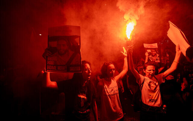 Einav Zangauker (center left, in black) hoists a picture of her son, captive captive Matan Zangauker, as protesters carry torches at a rally calling for the release of hostages held by Hamas in Gaza, in Jerusalem, June 27, 2024. (Chaim Goldberg/Flash90)