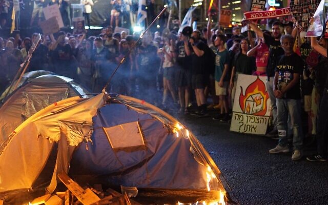 A tent is set ablaze in Tel Aviv as part of a protest on June 15, 2024, against what organizers say is the abandonment of northern Israel to Hezbollah attacks. A sign in the background reads "And the north? What about the north?" (Yehuda Bergstein / Pro Democracy Protest Movement) A tent is set ablaze in Tel Aviv as part of a protest on June 15, 2024, against what organizers say is the abandonment of northern Israel to Hezbollah attacks. A sign in the background reads "And the north? What about the north?" (Yehuda Bergstein / Pro Democracy Protest Movement)