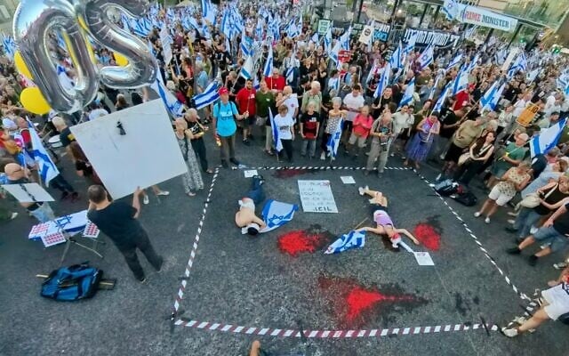 Demonstrators covered in red paint perform an art display titled "Am Israel Die," a word play on the Hebrew language slogan associated with with war on Hamas, which means "the People of Israel lives," at Tel Aviv's Democracy Square, June 22, 2024. (sha_b_p@/Pro-Democracy Protest Movement)