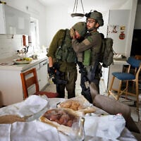 IDF Lotar unit soldiers crying on October 10, 2023, at the sight of the Kibbutz Kfar Aza home that still had challah from the family's Shabbat eve meal on the table when it was attacked by Hamas terrorists on October 7. (Courtesy Ziv Koren/Polaris)