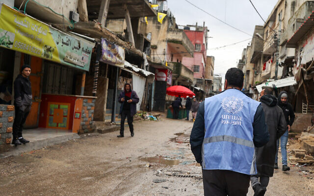 A man wearing a jacket bearing the logo of the United Nations Relief and Works Agency for Palestine Refugees (UNRWA), walks along a street devastated by the passage of Israeli military vehicles and bulldozers during raids, in the refugee camp of Balata in the West Bank on February 4, 2024. (Jaafar Ashtiyeh/AFP) A man wearing a jacket bearing the logo of the United Nations Relief and Works Agency for Palestine Refugees (UNRWA), walks along a street devastated by the passage of Israeli military vehicles and bulldozers during raids, in the refugee camp of Balata in the West Bank on February 4, 2024. (Jaafar Ashtiyeh/AFP)