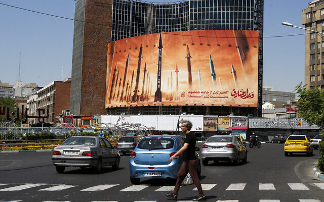 A man crosses a street as motorists drive past a billboard depicting Iranian ballistic missiles in service in Tehran on April 19, 2024. (AFP) A man crosses a street as motorists drive past a billboard depicting Iranian ballistic missiles in service in Tehran on April 19, 2024. (AFP)