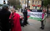 Campaigners calling for an end to the war in Gaza hold a flag promoting Vaz Shabir, an independent candidate in the forthcoming general election, in the town center of Keighley, northwest England, on June 14, 2024. (Oli SCARFF / AFP)