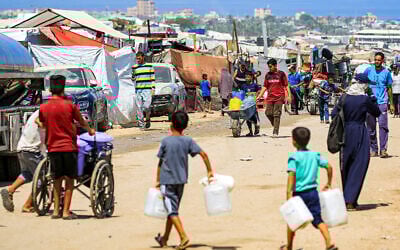 Boys walk with jerrycans to fill up from a water truck in Rafah in the southern Gaza Strip on June 25, 2024. (Eyad Baba / AFP)