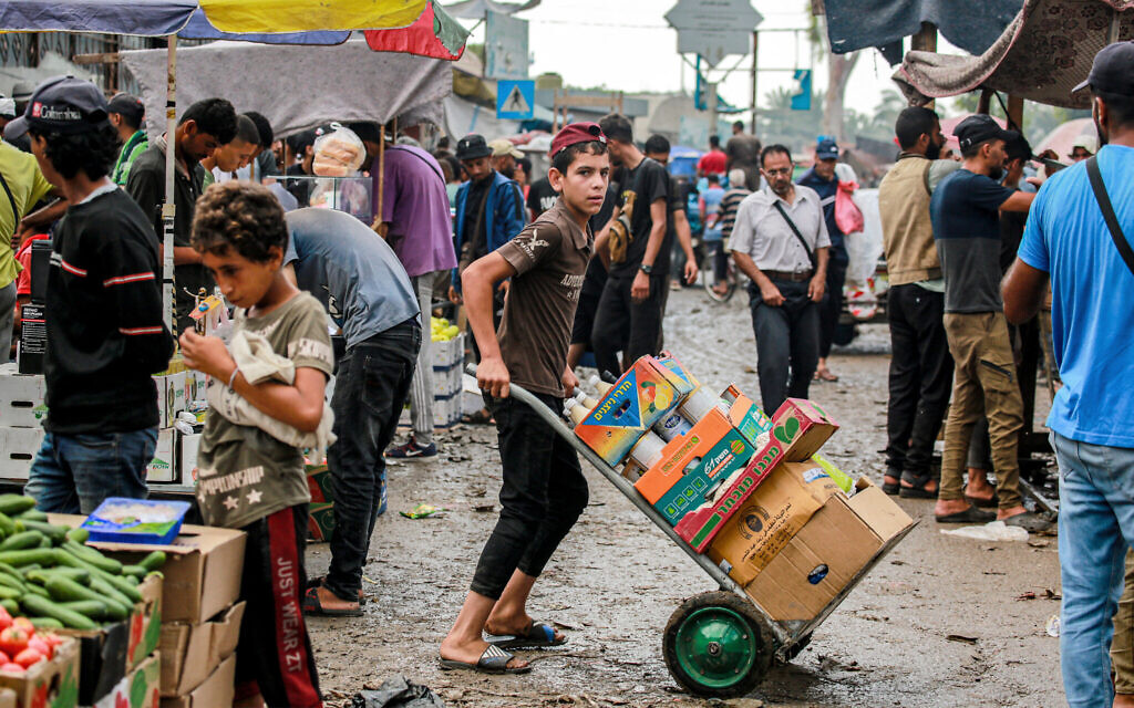 A boy pushes a cart loaded with boxes of canned food in Deir el-Balah in the central Gaza Strip on July 2, 2024. (Bashar Taleb / AFP)
