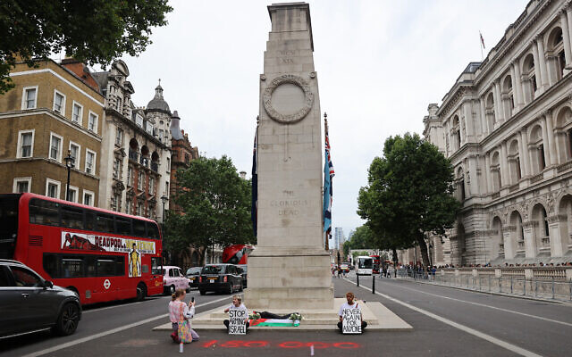 Youth Demand activists hold placards reading "Stop arming Israel" and "Never again for anyone" after laying flowers and a Palestinian flag at the Cenotaph war memorial in central London on July 15, 2024. (CARLOS JASSO / AFP)
