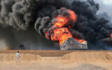 A man walks near to a raging fire at oil storage tanks a day after Israeli strikes on Yemen's Houthi-held Hodeida port on July 21, 2024. (AFP)