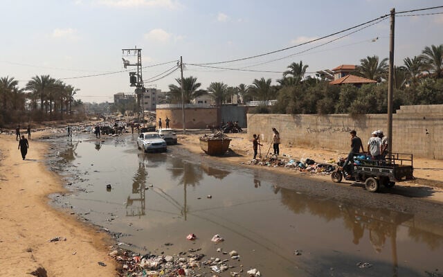 Palestinians walk past a pool of sewage water on a street in Deir el-Balah in the central Gaza Strip as municipal infrastructures fail amid the ongoing war in the Palestinian coastal territory, July 23, 2024(Eyad BABA / AFP) Palestinians walk past a pool of sewage water on a street in Deir el-Balah in the central Gaza Strip as municipal infrastructures fail amid the ongoing war in the Palestinian coastal territory, July 23, 2024(Eyad BABA / AFP)