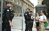 Visitors speak with French gendarmes guarding a restricted area with barriers on the Rivoli Street, near the Louvre Museum, central Paris, on July 23, 2024, ahead of Paris 2024 Olympic and Paralympic Games. (Natalia Kolesnikova/AFP)