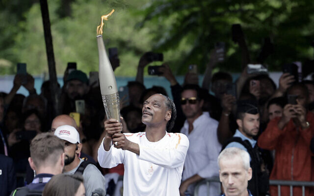 US rapper Snoop Dogg holds the torch as part of the 2024 Paris Olympic Games Torch Relay, on the day of the opening ceremony, in Saint-Denis, outside Paris, on July 26, 2024. (Stephane De Sakutin/AFP) US rapper Snoop Dogg holds the torch as part of the 2024 Paris Olympic Games Torch Relay, on the day of the opening ceremony, in Saint-Denis, outside Paris, on July 26, 2024. (Stephane De Sakutin/AFP)