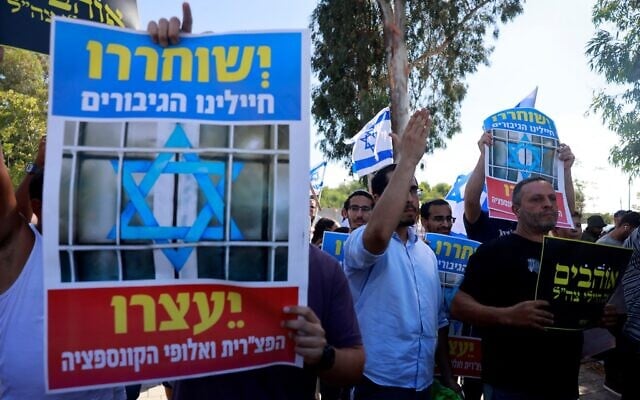 Demonstrators, one holding a poster that reads, "Our heroic soldiers should be released," protest against the detention of military reservists suspected of severely abusing a Palestinian terror suspect, in front of a military court in Beit Lid army base near Kfar Yona on July 30, 2024. (Menahem Kahana/AFP) Demonstrators, one holding a poster that reads, "Our heroic soldiers should be released," protest against the detention of military reservists suspected of severely abusing a Palestinian terror suspect, in front of a military court in Beit Lid army base near Kfar Yona on July 30, 2024. (Menahem Kahana/AFP)