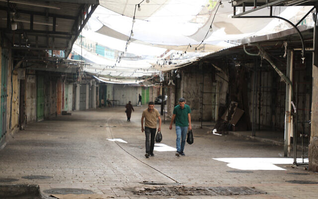 Palestinians walk through a deserted commercial area in Hebron in the West Bank during a general strike on July 31, 2024, following the assassination of Hamas chief Ismail Haniyeh in Iran overnight. (Photo by MOSAB SHAWER / AFP) Palestinians walk through a deserted commercial area in Hebron in the West Bank during a general strike on July 31, 2024, following the assassination of Hamas chief Ismail Haniyeh in Iran overnight. (Photo by MOSAB SHAWER / AFP)
