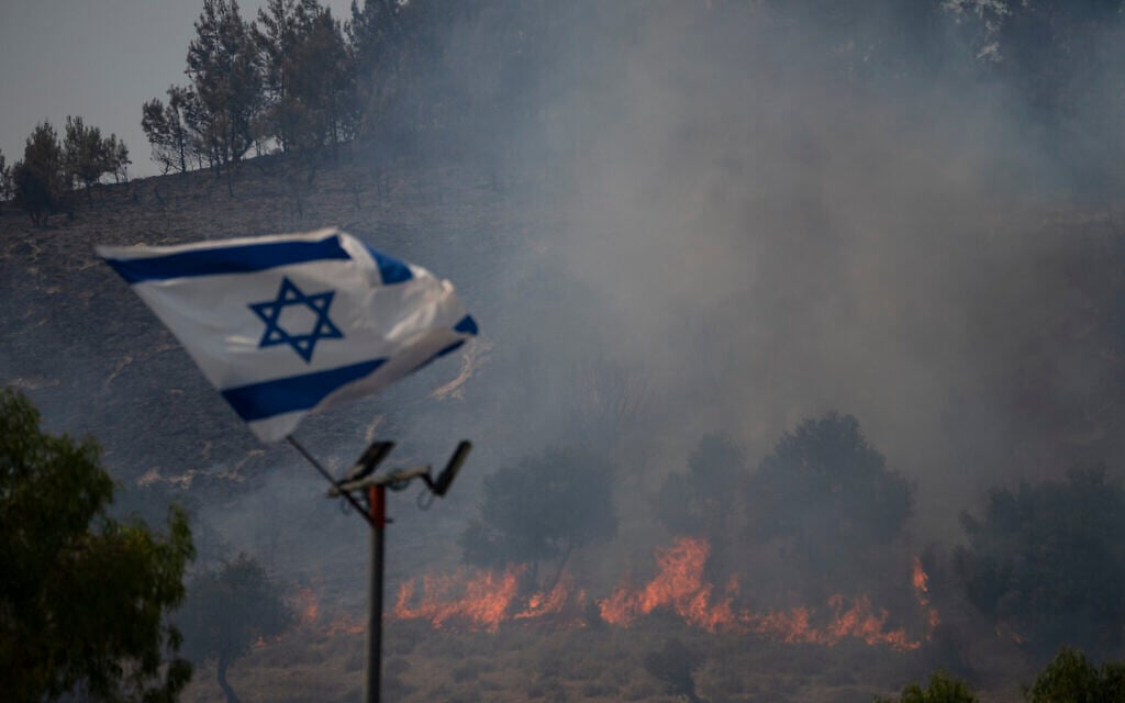 An Israeli flag flutters next to a fire burning in an area near the border with Lebanon, in Safed, June 12, 2024. (AP Photo/Leo Correa, File) An Israeli flag flutters next to a fire burning in an area near the border with Lebanon, in Safed, June 12, 2024. (AP Photo/Leo Correa, File)