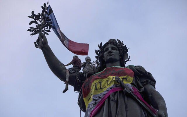 Statue of Republique plaza is decorated by flags as people gather at a protest against the far-right, July 3, 2024 in Paris (AP Photo/Louise Delmotte)