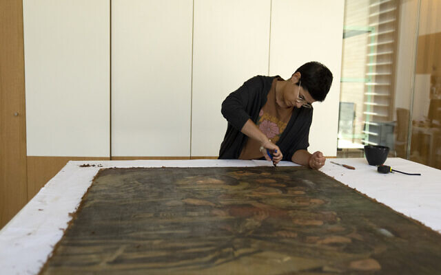 Sarah Reichert restores a painting in a conservation lab during the inauguration of The Moshal Shoah Legacy Campus and The David and Fela Shapell Family Collections Center, at Yad Vashem in Jerusalem, July 8, 2024. (AP Photo/Maya Alleruzzo)