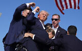 Presumptive Republican presidential candidate former president Donald Trump is surrounded by US Secret Service agents at a campaign rally, July 13, 2024, in Butler, Pennsylvania. (Evan Vucci/AP)
