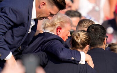 Republican US presidential candidate former president Donald Trump is helped off the stage at a campaign event after being shot in his ear, July 13, 2024, in Butler, Pennsylvania. (AP Photo/ Gene J. Puskar)