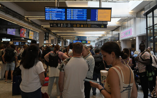 Travelers check trains on an electronic board at the Gare de Montparnasse, at the 2024 Summer Olympics, Friday, July 26, 2024, in Paris, France. (AP Photo/Yasin Dar)