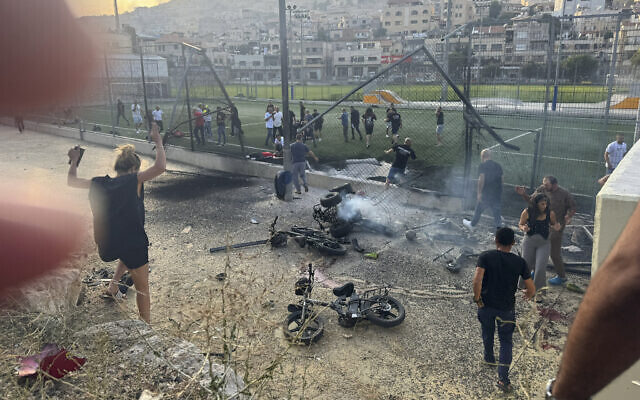 Residents rush to help injured children moments after a Hezbollah rocket attack hit a soccer field in the Druze town of Majdal Shams in the Golan Heights, July 27, 2024. (Hassan Shams/AP) Residents rush to help injured children moments after a Hezbollah rocket attack hit a soccer field in the Druze town of Majdal Shams in the Golan Heights, July 27, 2024. (Hassan Shams/AP)