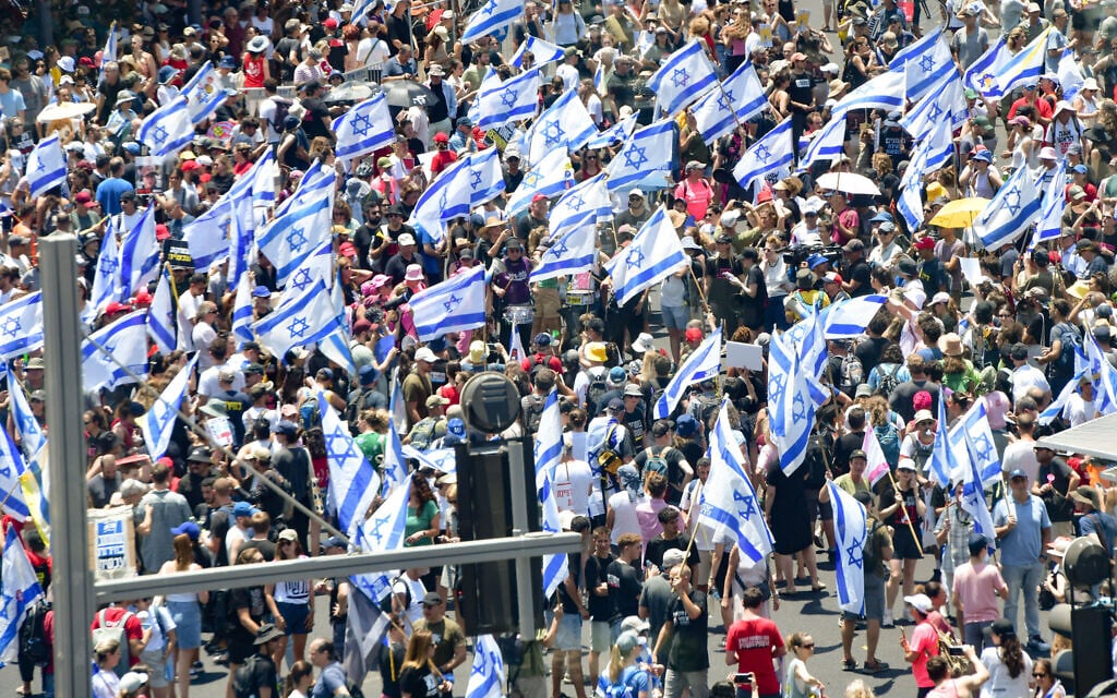 Demonstrators march with Israeli flags during a protest marking nine months since the start of the war and calling for elections and the release of hostages held in the Gaza Strip in Tel Aviv, July 7, 2024 (Avshalom Sassoni/Flash90)