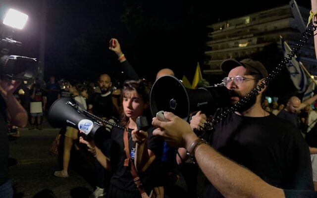 Anti-government activist Tomer Lev gives an impromptu speech instructing protesters to march silently to Prime Minister Benjamin Netanyahu's residence, in light of a deadly Hezbollah attack on the Golan Heights, July 27, 2024. (Charlie Summers/Times of Israel)