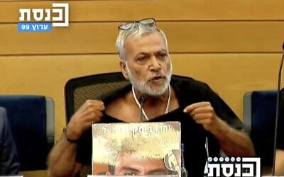 Bereaved father Shimon Buskila tears his shirt, a traditional Jewish act of mourning, as he speaks at a Knesset lobby session on work being done to conserve the site of the Supernova festival massacre, July 15, 2024. (Screenshot, Knesset Channel)