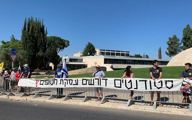 As part of a demonstration for a hostage deal, Hebrew University students in a human chain hold up a banner outside the Prime Minister's Office in Jerusalem which reads: 'Students demand a hostage deal!' on July 16, 2024. (Charlie Summers/Times of Israel)