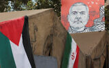 A banner with a picture of slain Hamas leader Ismail Haniyeh is displayed next to the Iran and Palestinian flags in a street in Tehran, August 12, 2024. (Majid Asgaripour/WANA/Reuters)
