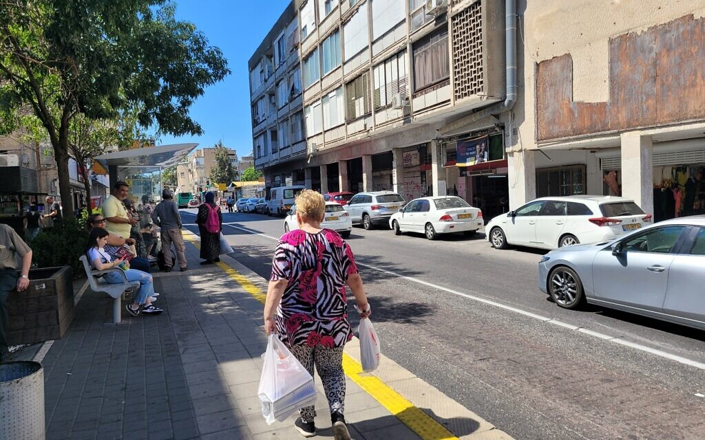A woman carries her shopping near Talpiot Market in Haifa on August 4, 2024. (Canaan Lidor/Times of Israel)
