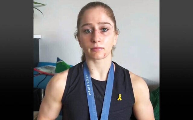 US Olympic wrestling gold medalist Amit Elor speaks against antisemitism while wearing a yellow hostages pin, August 9, 2024. (Video screenshot)