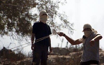 Illustrative: Jewish settlers swing sling shots during clashes with Palestinian close to the northern West Bank village of Burin on July 26, 2010. (Jaafar Ashtiyeh / AFP)