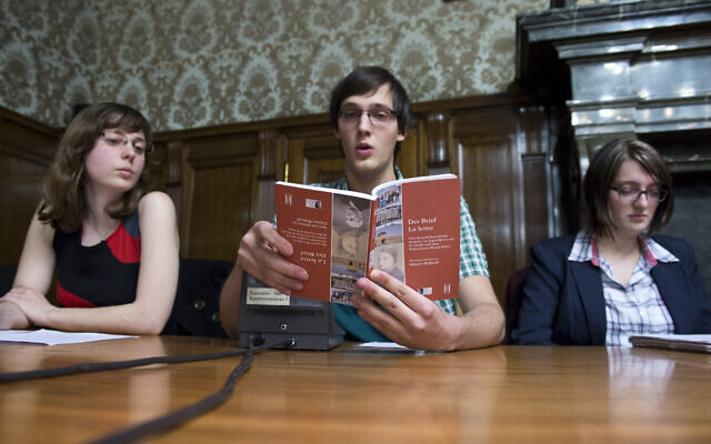 Illustrative: German high school students from the Reclam gymnasium Leipzig read excerpts of the bilingual book 'Der Brief/La Lettre' detailing the results of their research into the life of Holocaust victim Martin Kober at a book launch ceremony in Leipzig's town hall, November 27, 2012. (Photo by JOHN MACDOUGALL / AFP)