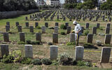 A gardener waters the lawn between the tombstones at the Commonwealth Gaza War Cemetery, commonly known as the British War Cemetery and in which are interred the remains of 3217 Allied soldiers who died during World War I, in Gaza City on September 28, 2022. (Mahmud Hams/AFP)