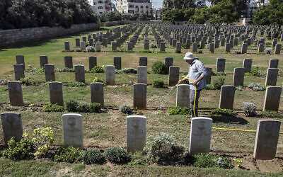 A gardener waters the lawn between the tombstones at the Commonwealth Gaza War Cemetery, commonly known as the British War Cemetery and in which are interred the remains of 3217 Allied soldiers who died during World War I, in Gaza City on September 28, 2022. (Mahmud Hams/AFP)
