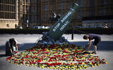 Volunteers lays flowers at an installation by the charity Oxfam, depicting a Mark-84 2,000-pound bomb with the words 'Stop Arming Israel,' opposite the Houses of Parliament in central London on July 30, 2024. (HENRY NICHOLLS / AFP)
