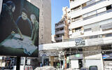 A billboard displaying an image of late Iranian Quds Force chief Qasem Soleimani (R) and Hezbollah leader Hassan Nasrallah (C) stands in front of a building targeted in an Israeli military strike on a Hezbollah commander in Beirut the previous day, on July 31, 2024 (ANWAR AMRO / AFP)