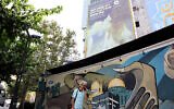 A man walks under an anti-Israel billboard reading in Persian, 'Tel Aviv will be not safe anymore' at Palestine Square in Tehran on July 31, 2024 (AFP)