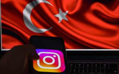This picture taken in Istanbul on August 2, 2024, shows the logo of the social network Instagram on a smartphone with the Turkish flag in the background. (Yasin Akgul/AFP)