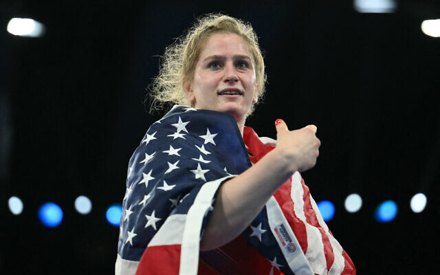 US' Amit Elor celebrates with her national flag after beating Kyrgyzstan's Meerim Zhumanazarova in their women's freestyle wrestling final match during the Paris 2024 Olympic Games, on August 6, 2024. (Luis Robayo/AFP)