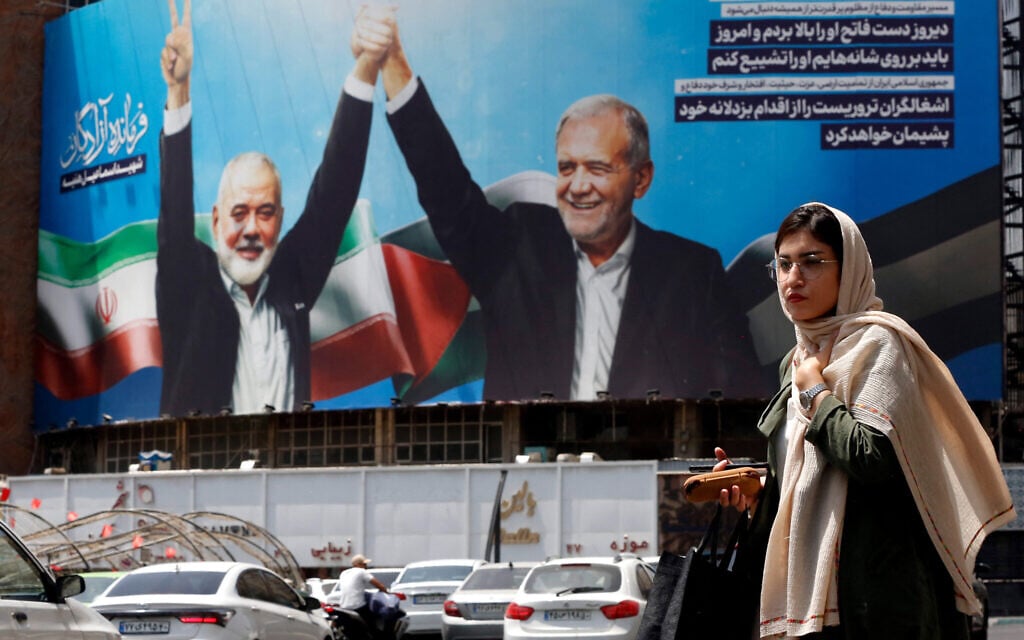 A woman walks past a huge billboard depicting Iranian President Masoud Pezeshkian (R) and slain Hamas leader Ismail Haniyeh at Tehran's Valiasr square on August 8, 2024. (AFP)