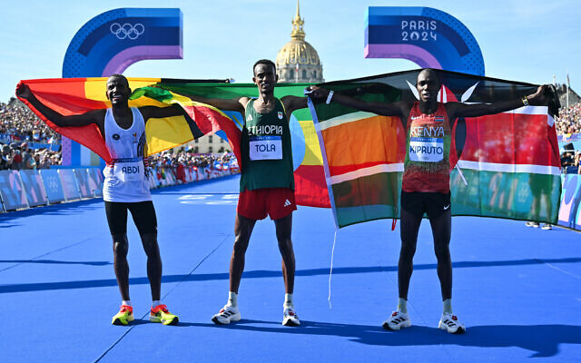 Winner Ethiopia's Tamirat Tola (C), second placed Belgium's Bashir Abdi (L) and third placed Kenya's Benson Kipruto celebrate after the men's marathon of the athletics event at the Paris 2024 Olympic Games at Invalides in Paris on August 10, 2024. (Andrej Isakovic/AFP) Winner Ethiopia's Tamirat Tola (C), second placed Belgium's Bashir Abdi (L) and third placed Kenya's Benson Kipruto celebrate after the men's marathon of the athletics event at the Paris 2024 Olympic Games at Invalides in Paris on August 10, 2024. (Andrej Isakovic/AFP)
