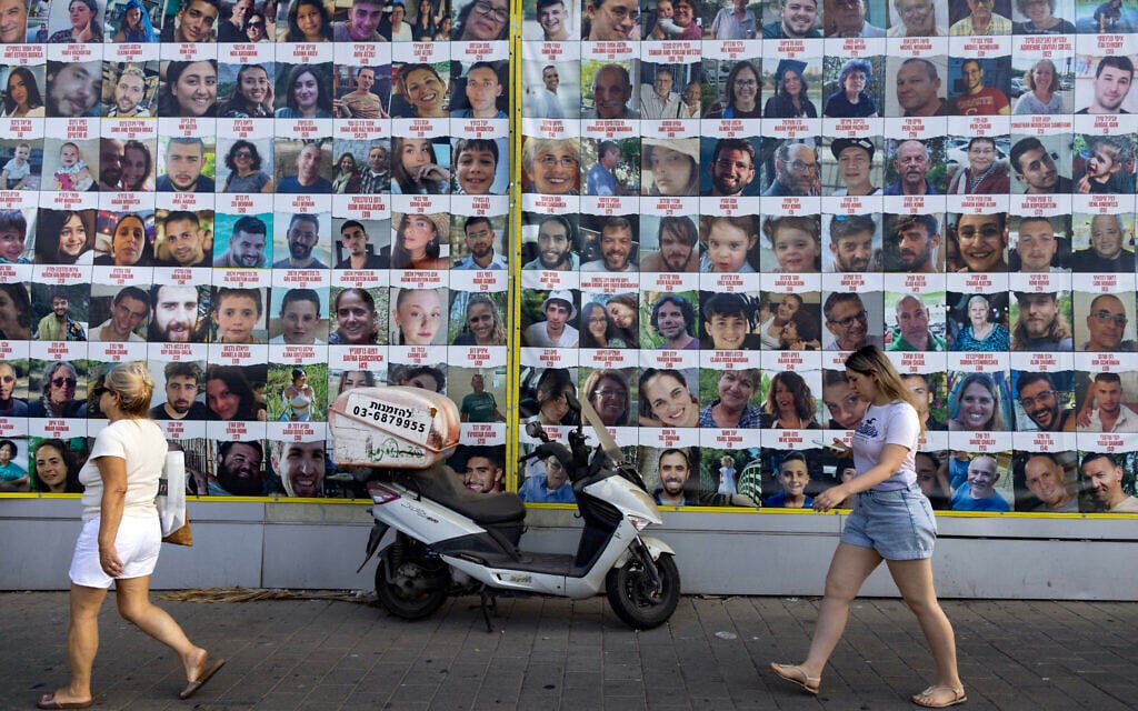 People walk past posters of Israelis held hostage by by Hamas in Gaza since October 7, in Tel Aviv on August 11, 2024 (Photo by Oren ZIV / AFP)