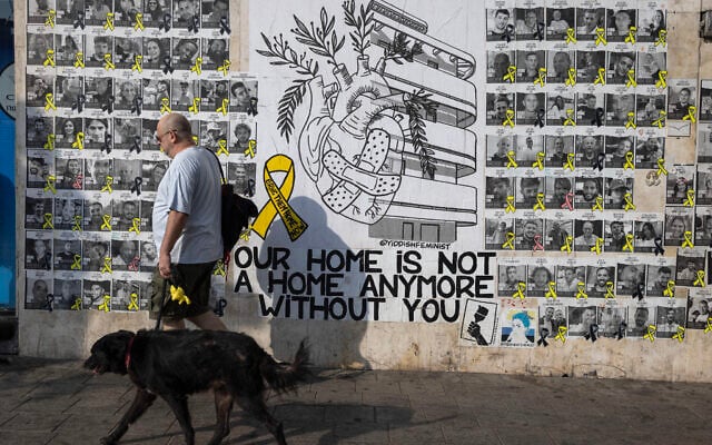 People walk past posters of Israelis held hostage in Gaza since October 7, on a street in Tel Aviv on August 13, 2024. (Oren ZIV / AFP)