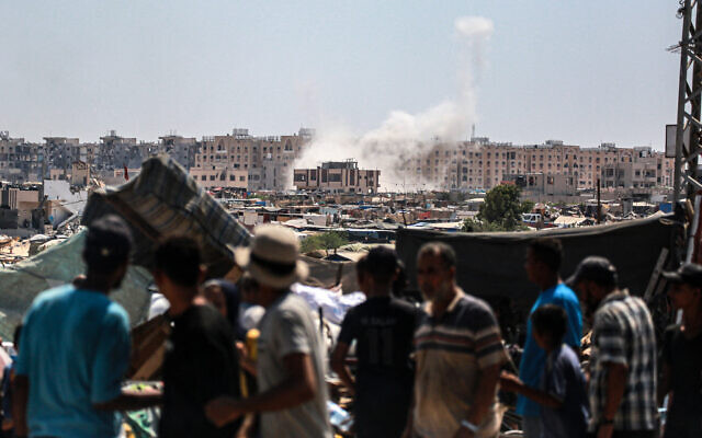 Displaced Palestinians watch from a makeshift camp as shells fired from Israeli tanks hit an area near the Hamad residential complex in Khan Yunis in the southern Gaza Strip on August 18, 2024 (Photo by Bashar TALEB / AFP) Displaced Palestinians watch from a makeshift camp as shells fired from Israeli tanks hit an area near the Hamad residential complex in Khan Yunis in the southern Gaza Strip on August 18, 2024 (Photo by Bashar TALEB / AFP)