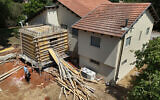 An aerial view shows a worker building a bomb shelter next to the house of an Israeli couple in Tel Mond in central Israel on August 22, 2024. (JACK GUEZ / AFP)